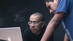 Two men looking at a laptop