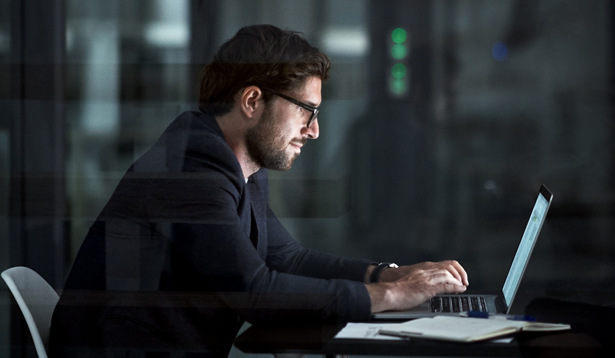 Man sitting behind laptop dark