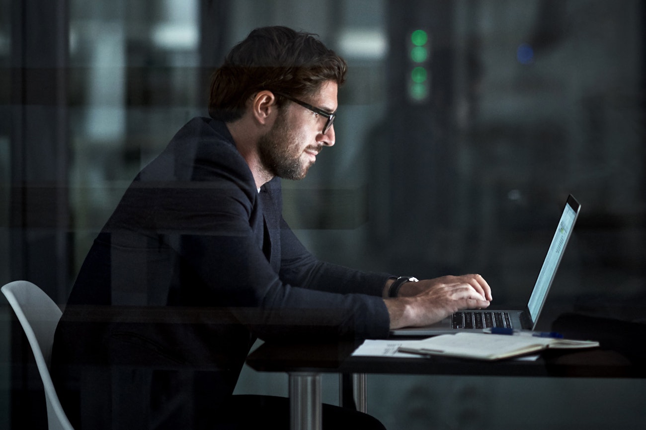 Man sitting behind laptop dark